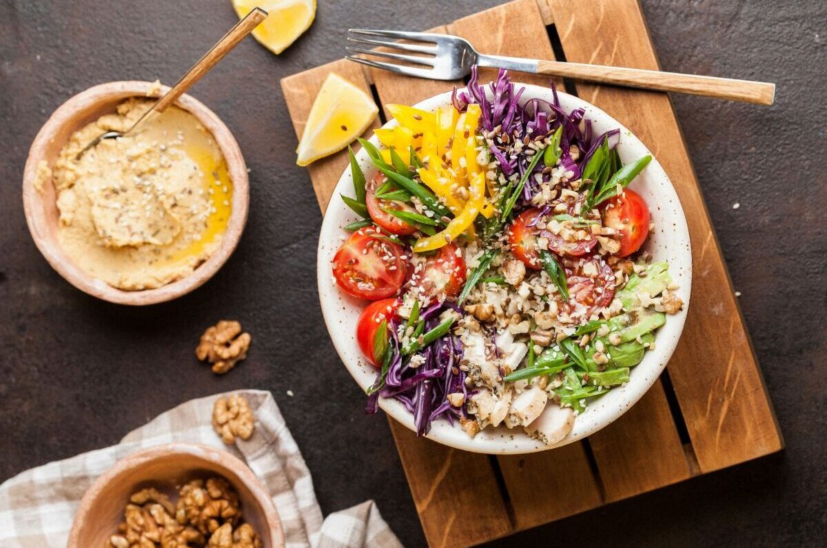 bowls of food with vegetables, hummus, and walnuts