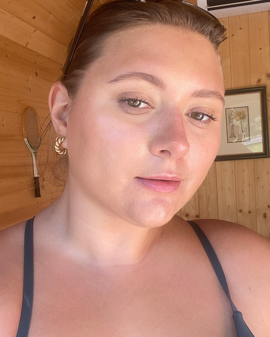 a person with a black garment and earrings in a room with a wood wall and a wood ceiling