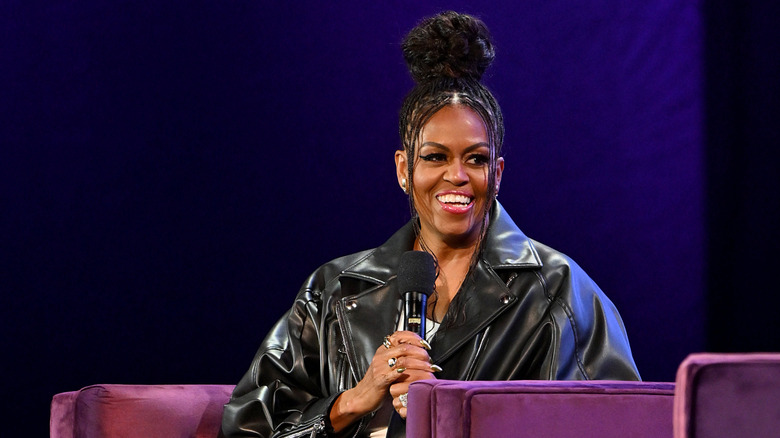 Michelle Obama holds microphone wearing leather jacket