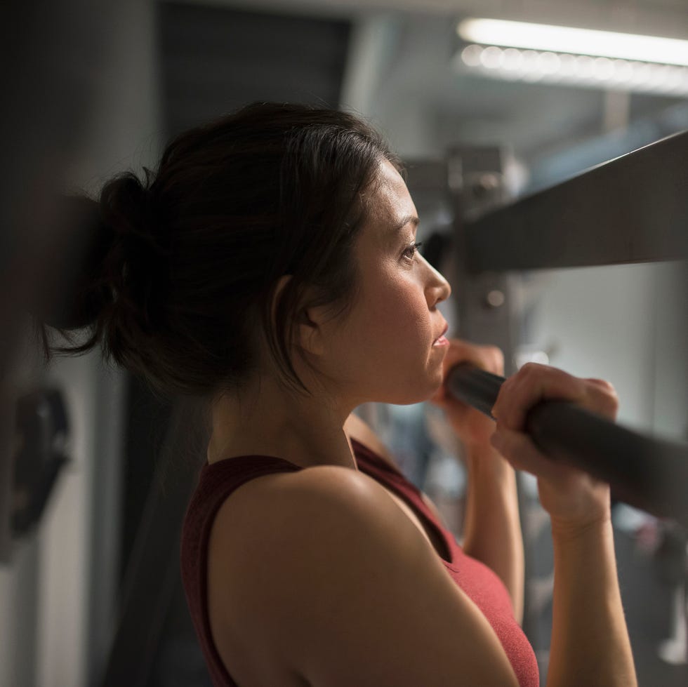 mixed race woman using exercise machine in gym