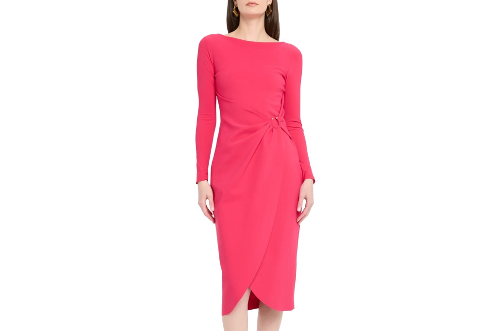 Woman wearing a coral pink long-sleeved boat neck dress with a side knot at the waist and a tulip hem skirt.