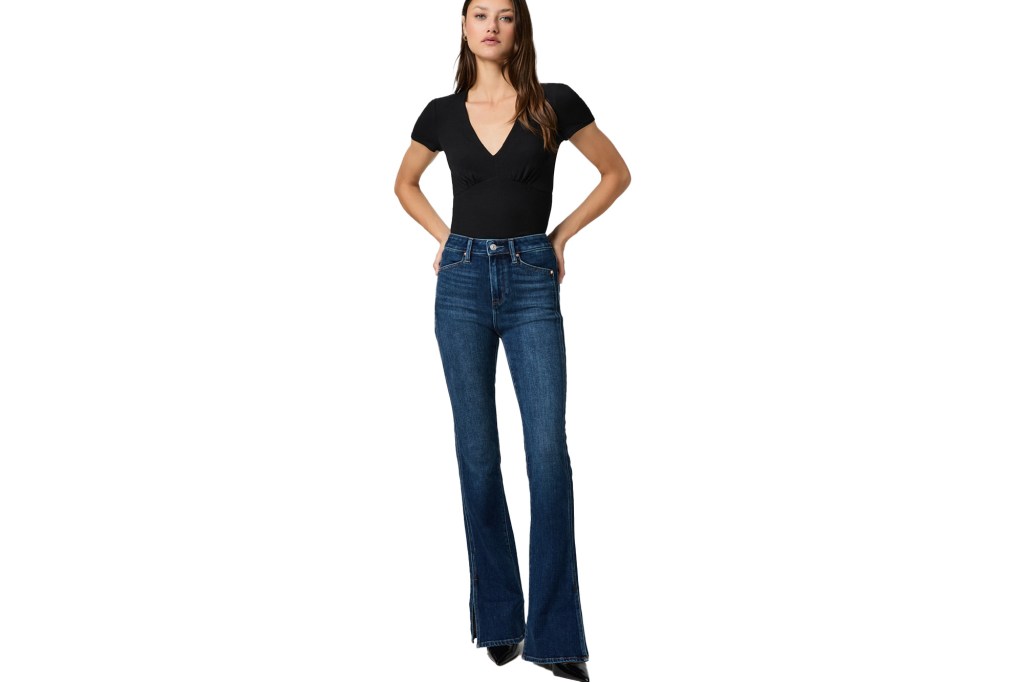 A woman posing in a short-sleeve V-neck shirt and flared jeans with slits.