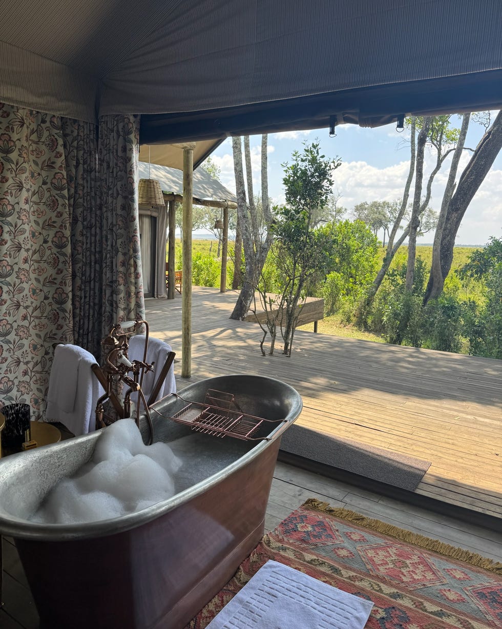 luxurious bathroom setting with a view featuring a metal bathtub filled with bubbles paradise plains kenya