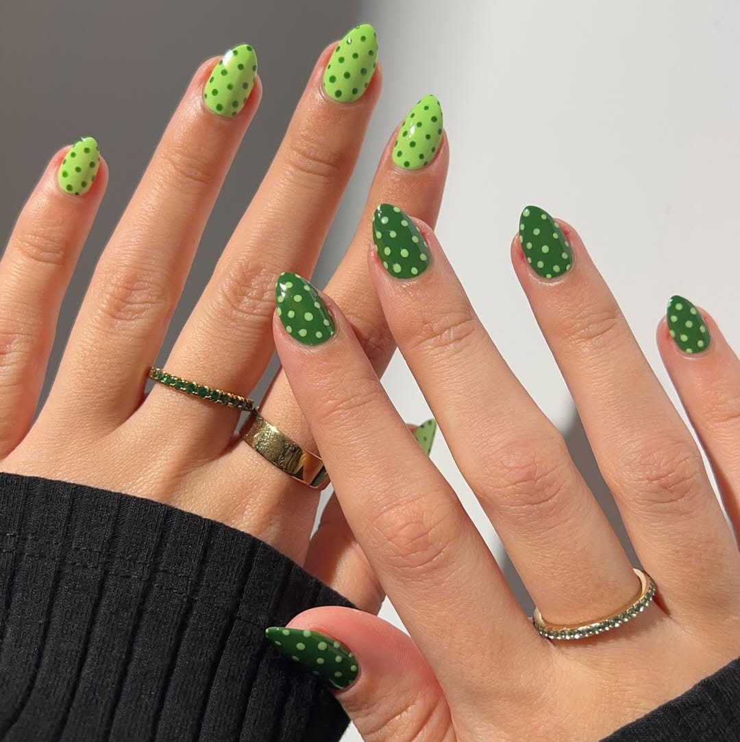 nail art featuring two hands with green polka dot manicures