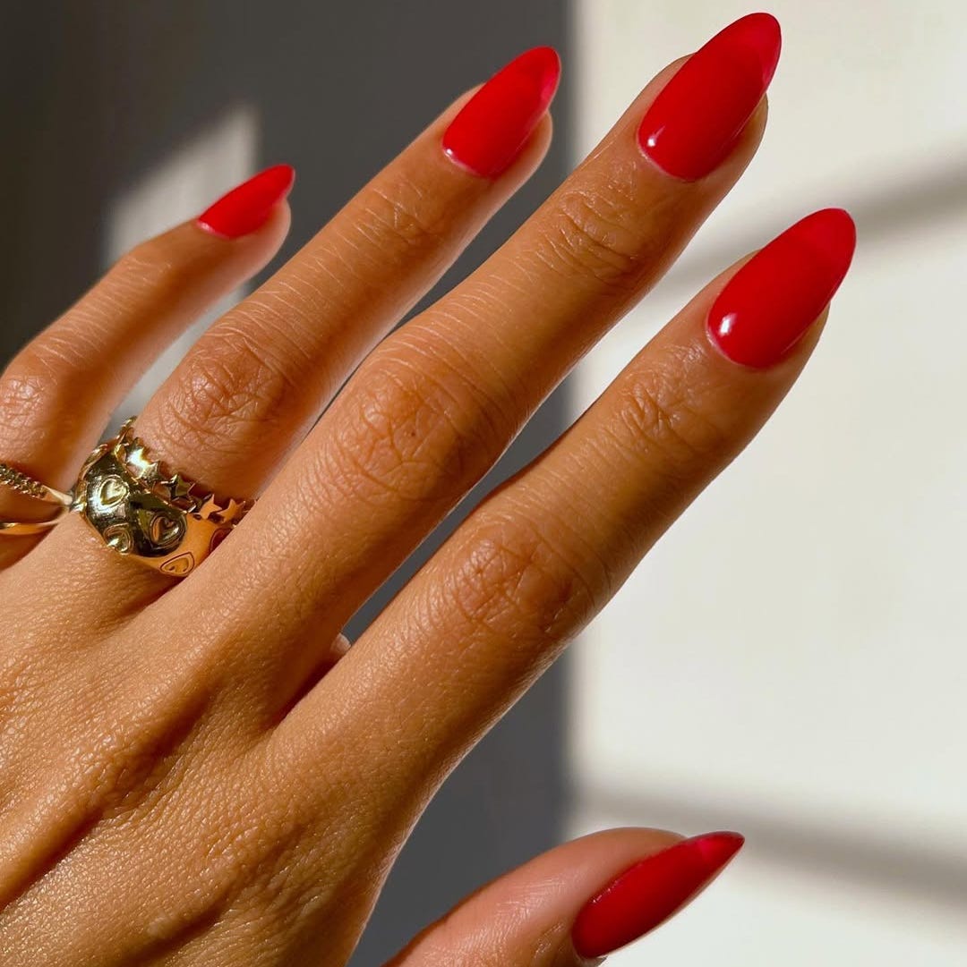 red manicured nails with rings on a hand
