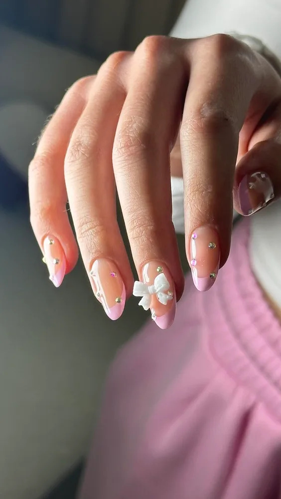 Fingers bent on nails stones and pink stripes with a white bow