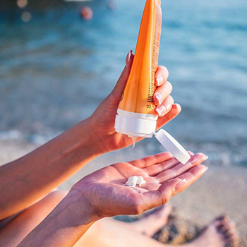 Person applying sunscreen while sitting on the beach