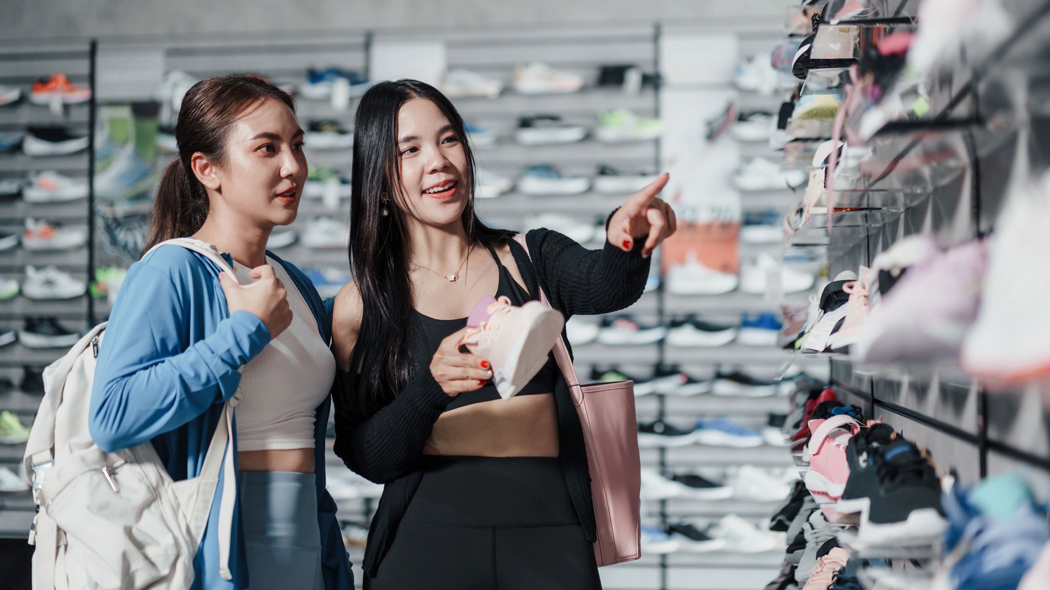 a picture of two young women shopping for running shoes in a store