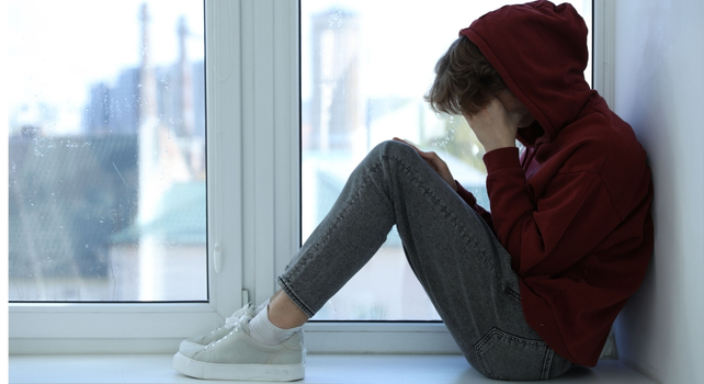 teenager hiding their face in their hands
