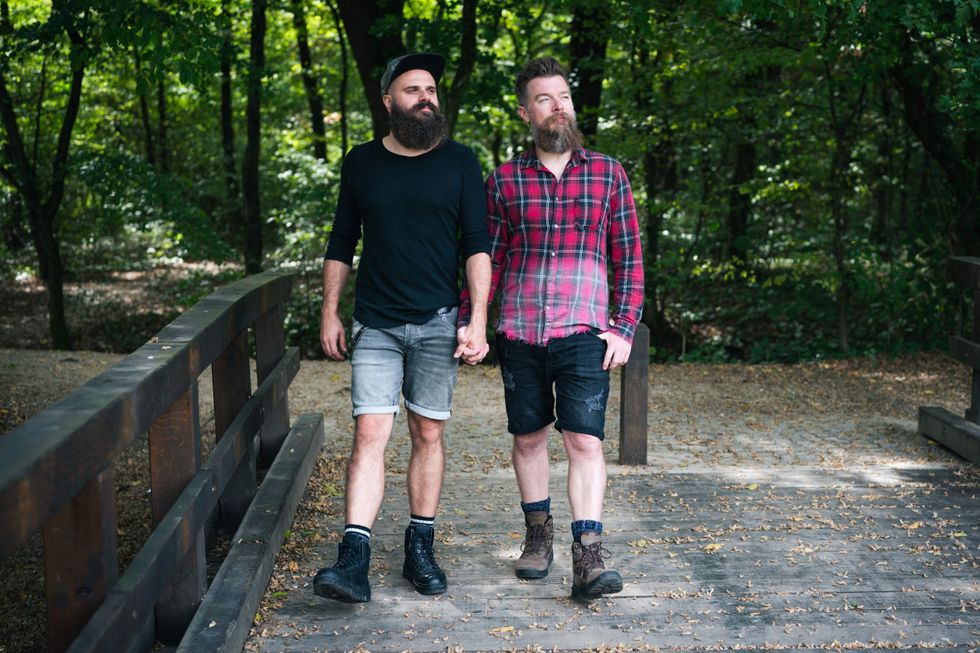 \u200bTwo men holding hands while walking in a park.