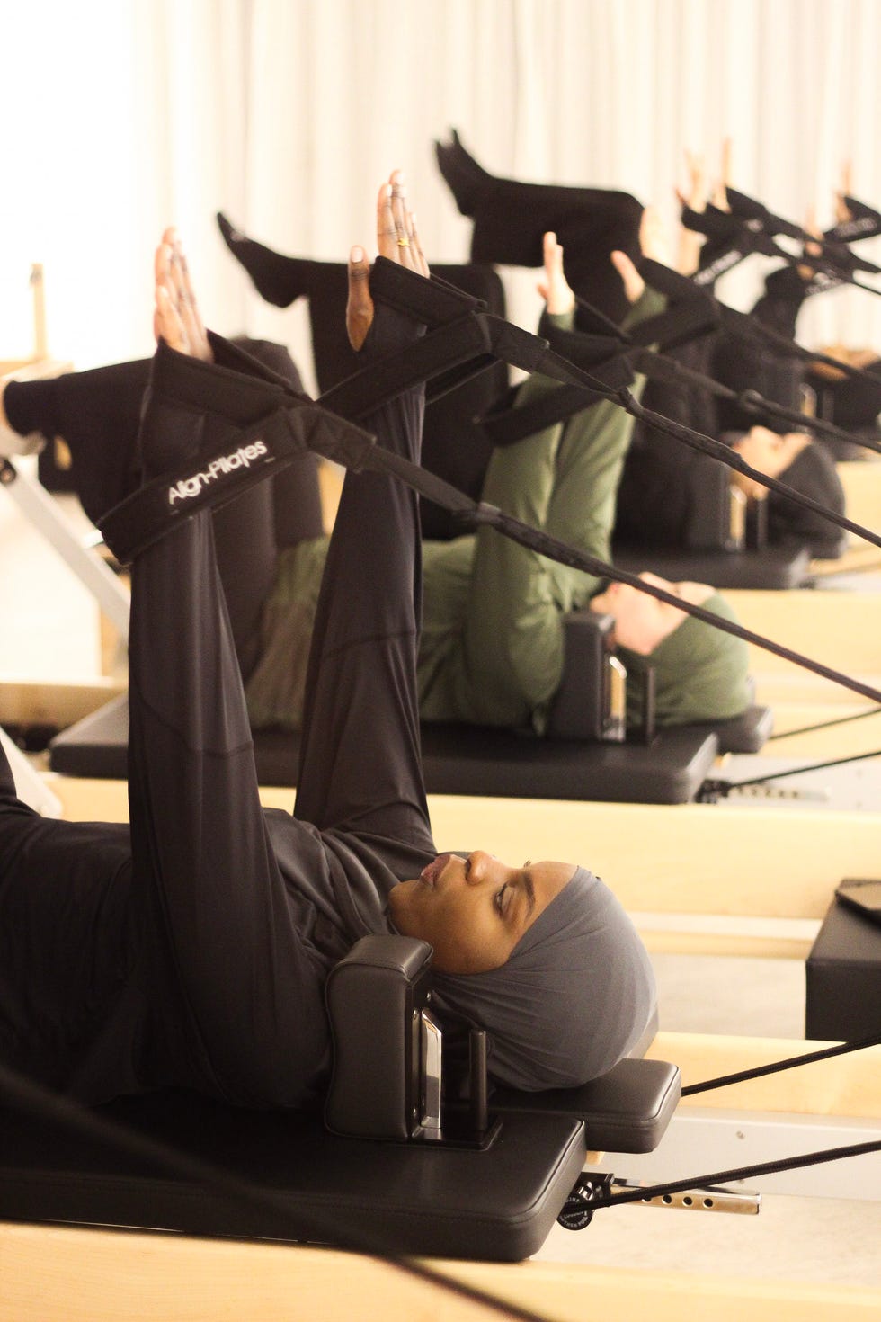 pilates class with participants engaged in leg exercises on reformer machines