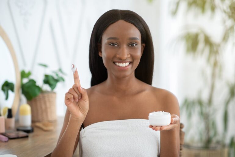 A person holding a bottle of skin creme with a finger up in the air.