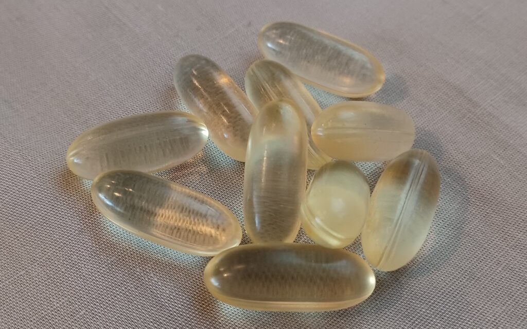 Vegan supplement capsules in a glass bottle, representing the types of anti-aging and dietary supplements scrutinized in recent cancer growth studies.