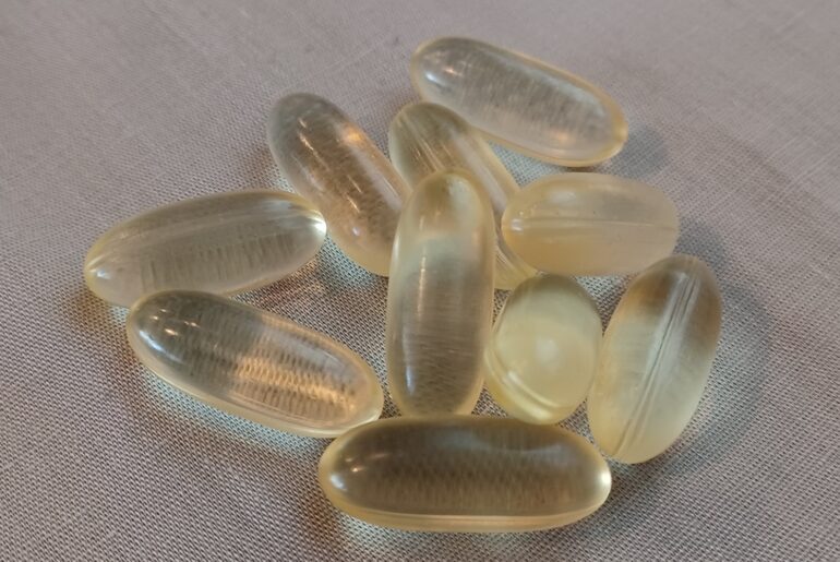 Vegan supplement capsules in a glass bottle, representing the types of anti-aging and dietary supplements scrutinized in recent cancer growth studies.