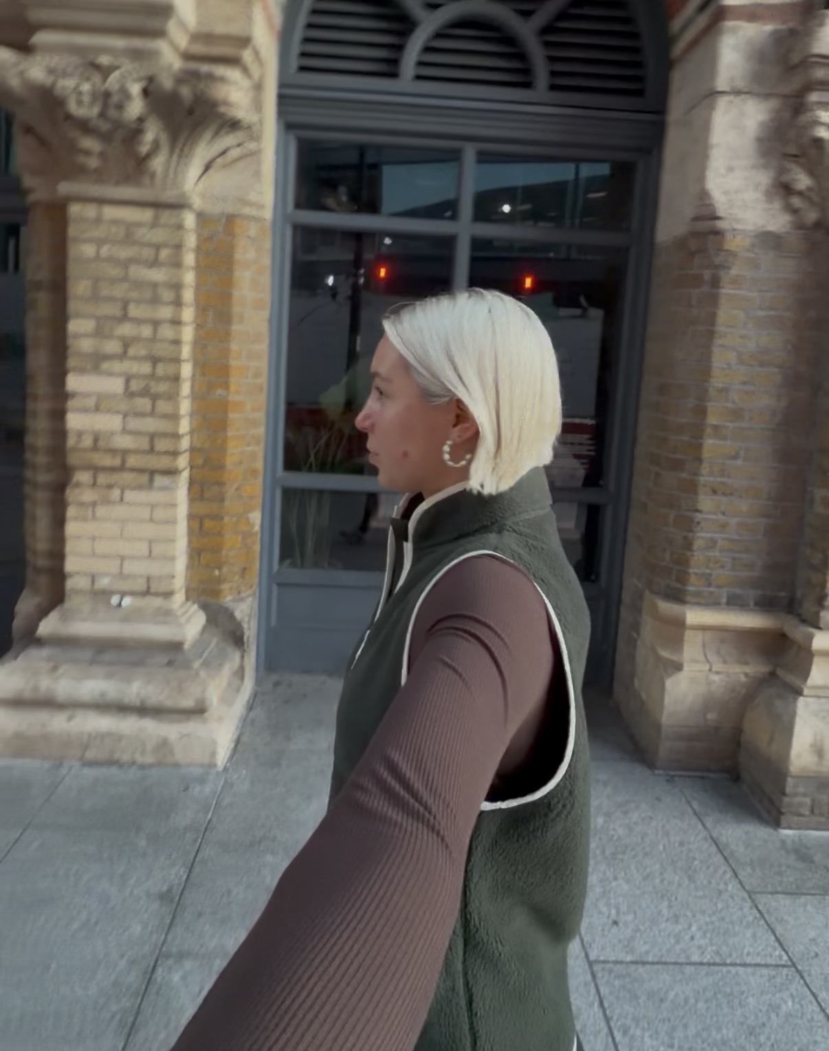 A side profile of a woman with blonde hair walking down a paving stoned street