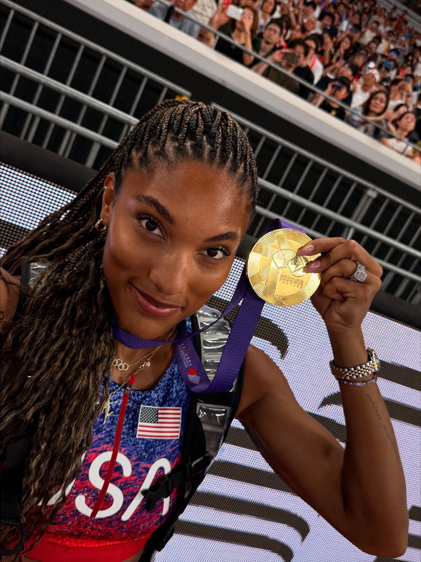Tara Davis-Woodhall holding her Olympic gold medal from the 2024 Paris Olympic Games.
