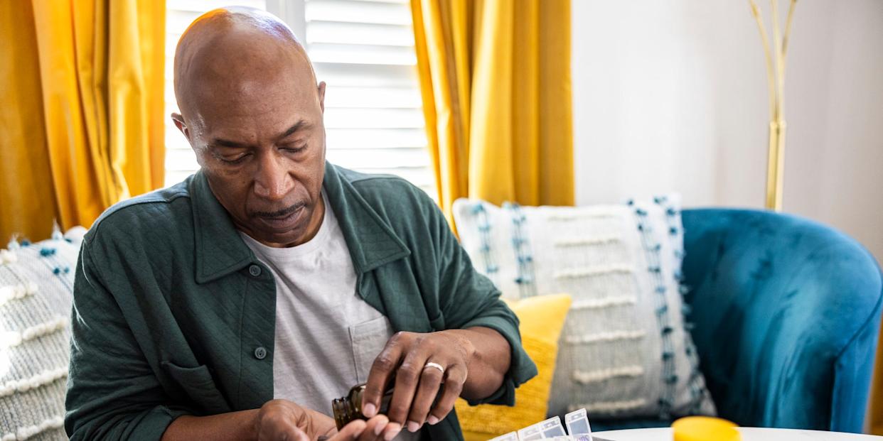 Senior man sorting prescription medications at kitchen table