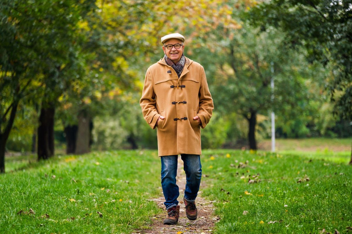 A happy old man walking through a park