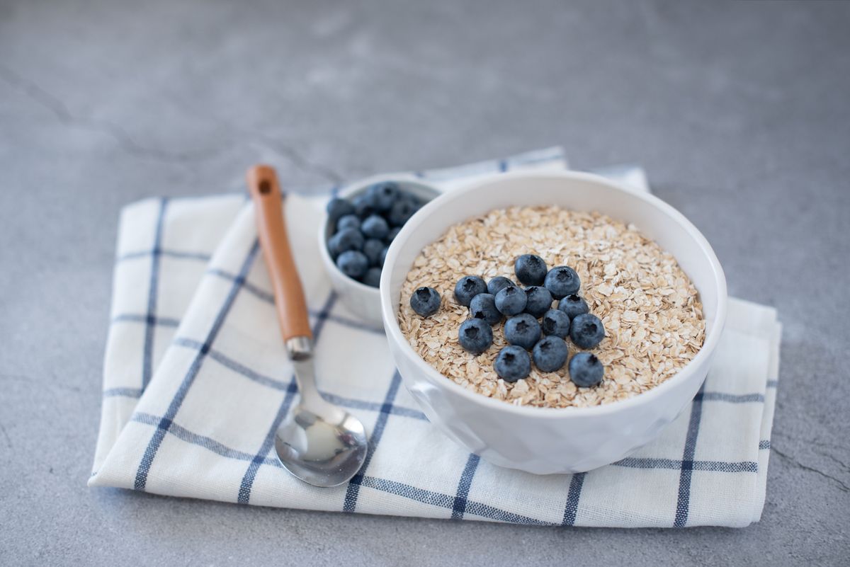Homemade oatmeal with blueberries and strawberries in bowl on gray concrete background. Healthy breakfast
