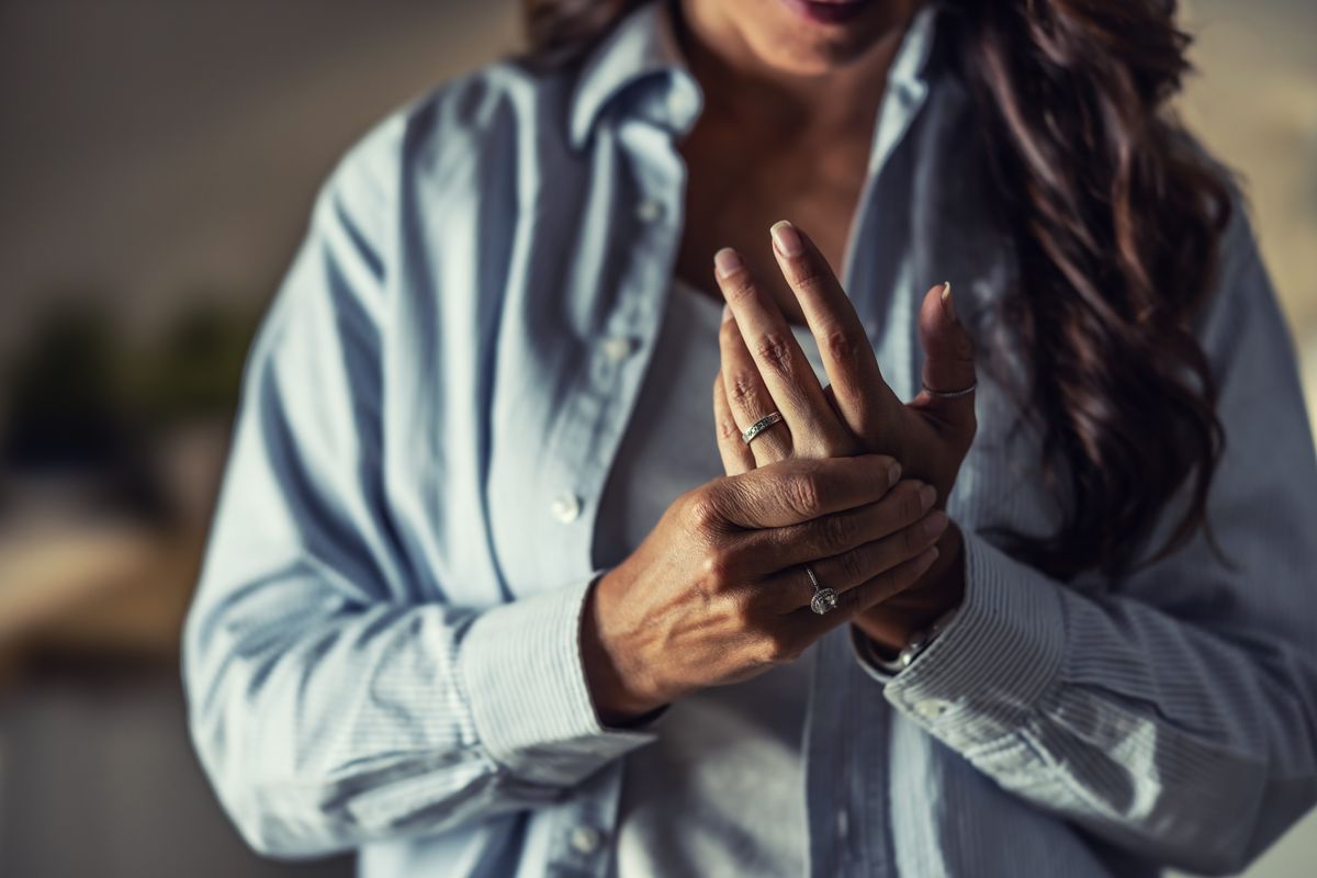 A woman holds her wrist, a classic gesture indicating pain