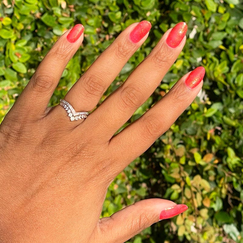 Hand with manicured nails and a decorative ring.