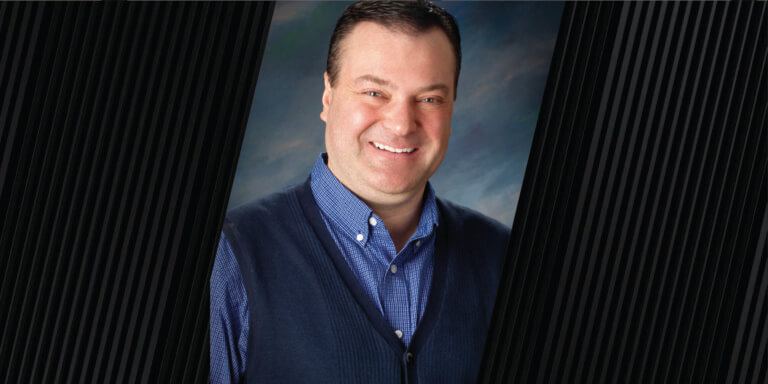 portrait of man wearing a blue button up shirt with a dark blue vest
