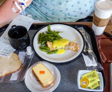 A photo of a tray of food in front of a hospitalized woman.