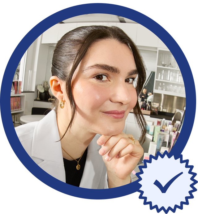 A person in a white coat holding their hand up to their face.