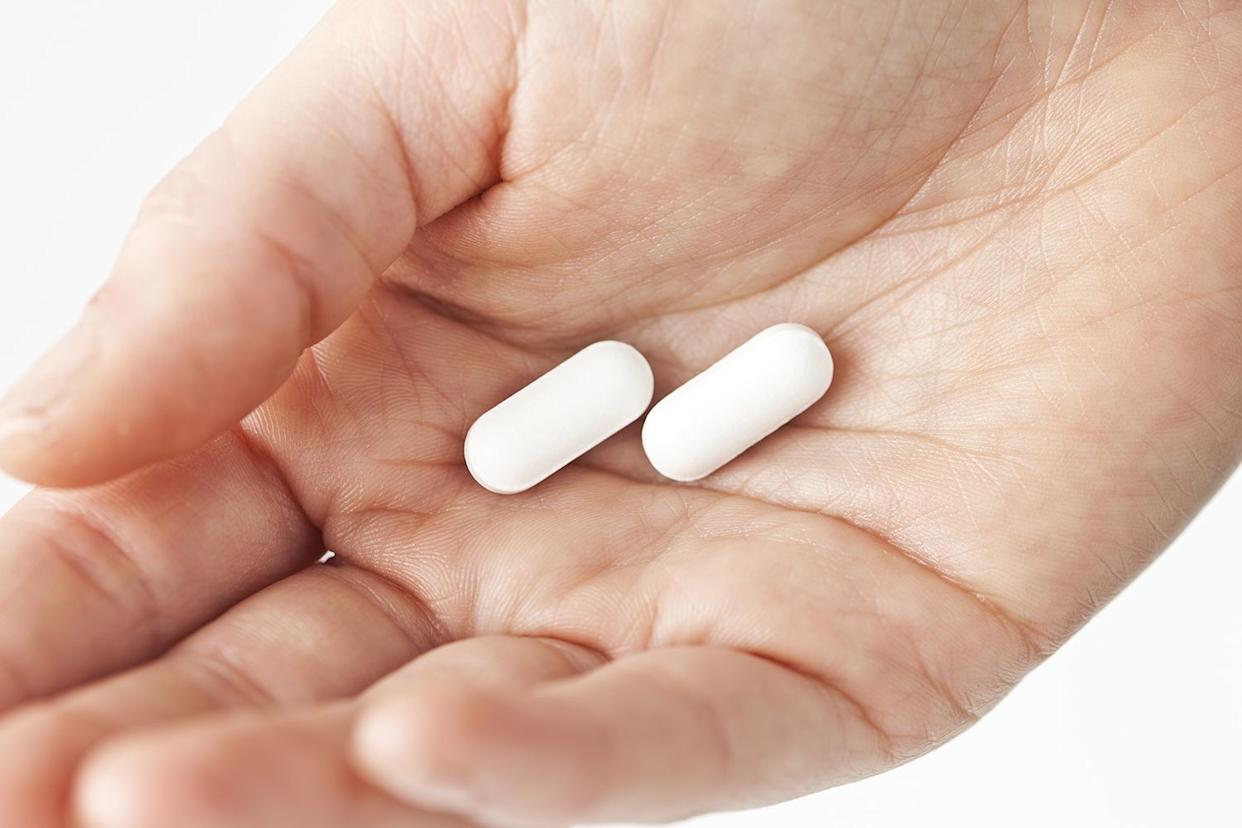Stock image of a woman holding white pillsCredit: Getty