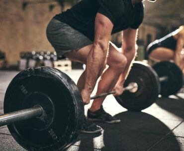 A business team deadlift training in the gym before heading to work.