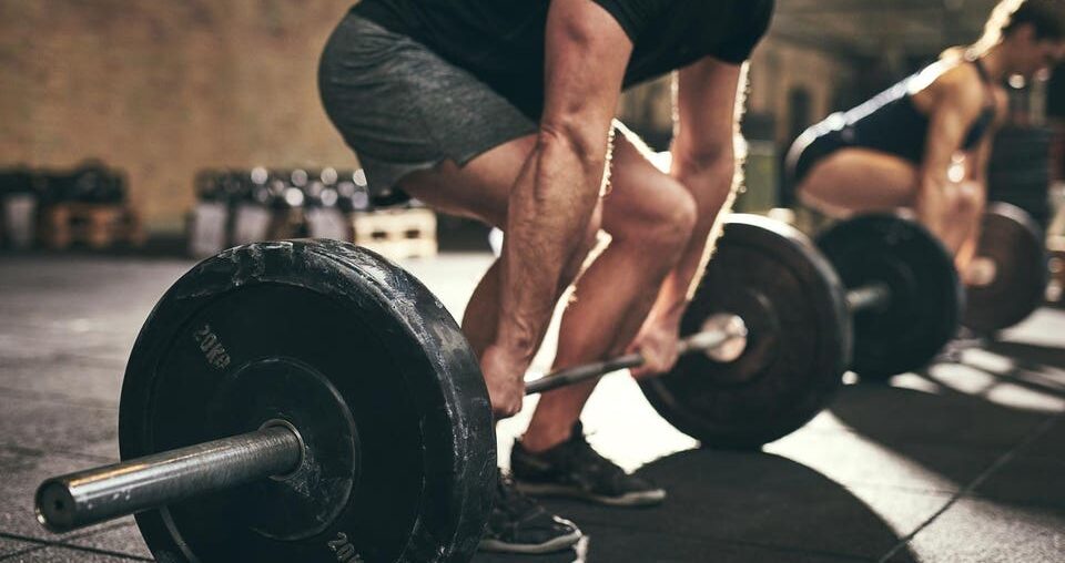 A business team deadlift training in the gym before heading to work.