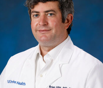 uci health neurologist dr brian hitt wearing a white coat in front of a blue studio background