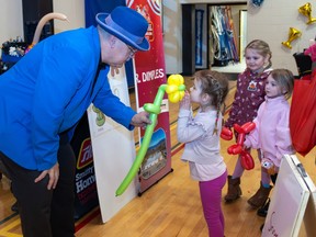Mr. Dimples handing balloon flower to little girl