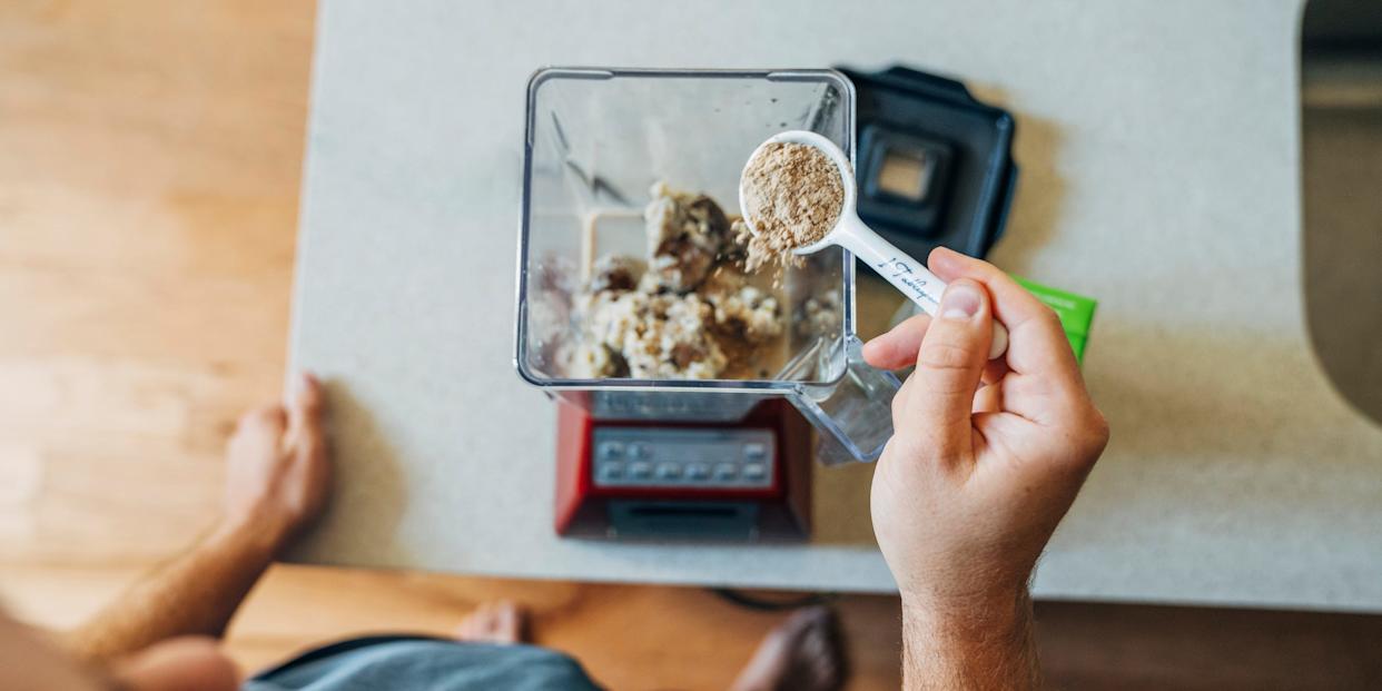 Man's hand putting putting collagen protein powder into blender for smoothie