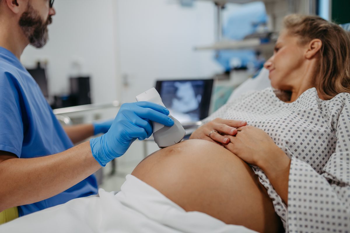 Ob/gyn doctor doing ultrasound of baby on pregnant woman. Woman having sonogram. Prenatal visit or care during third trimester of pregnancy. Pregnant woman on pregnancy check-up in gynaecologist doctor’s office.