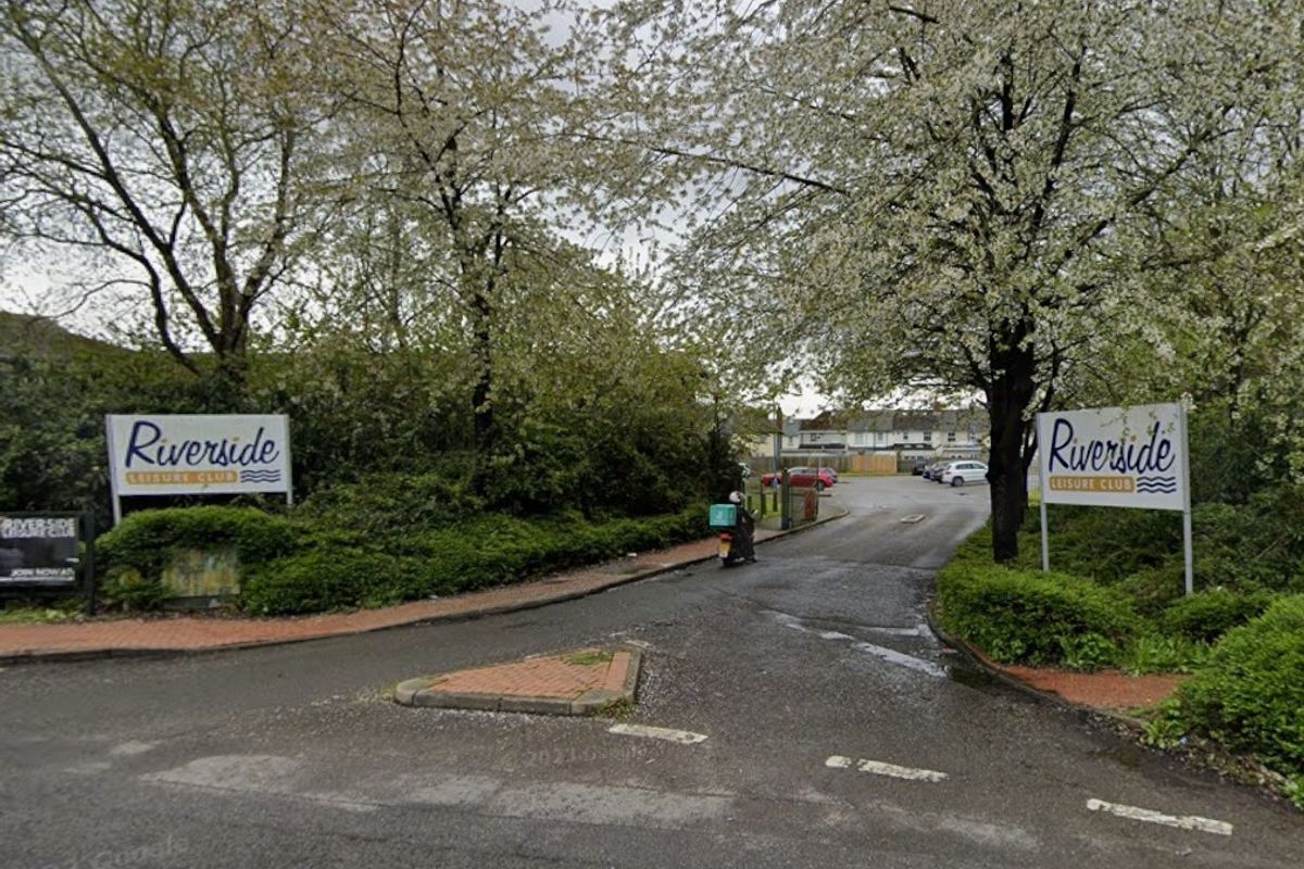 An exterior view of the entrance to Riverside Leisure Club, which has signs either side of an entrance road