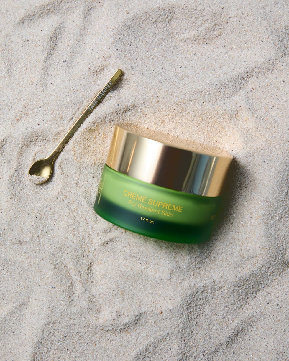 Skincare cream jar and small spoon on sand.