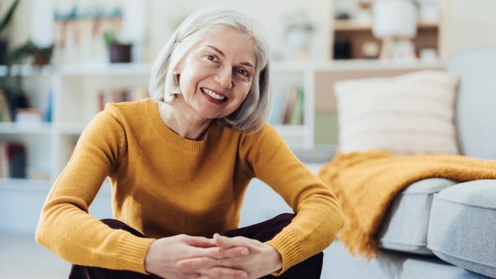 A woman in a yellow top smiling after learning how to lower her blood pressure fast