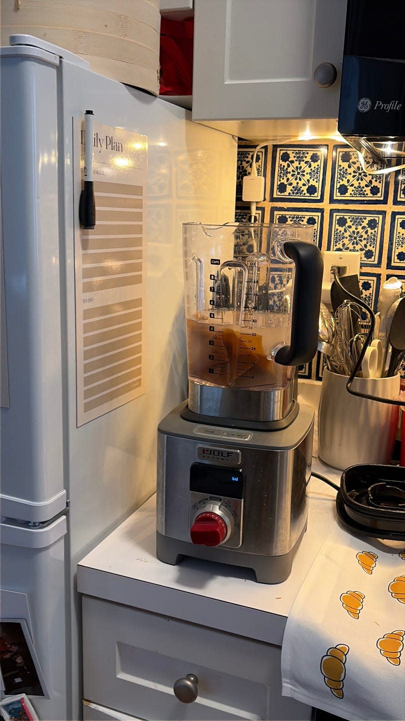 Blender on kitchen counter with contents and nearby utensils.