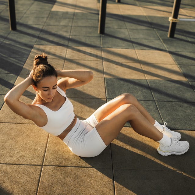 Woman training abs muscles on sports ground. Street workout and sports concept.