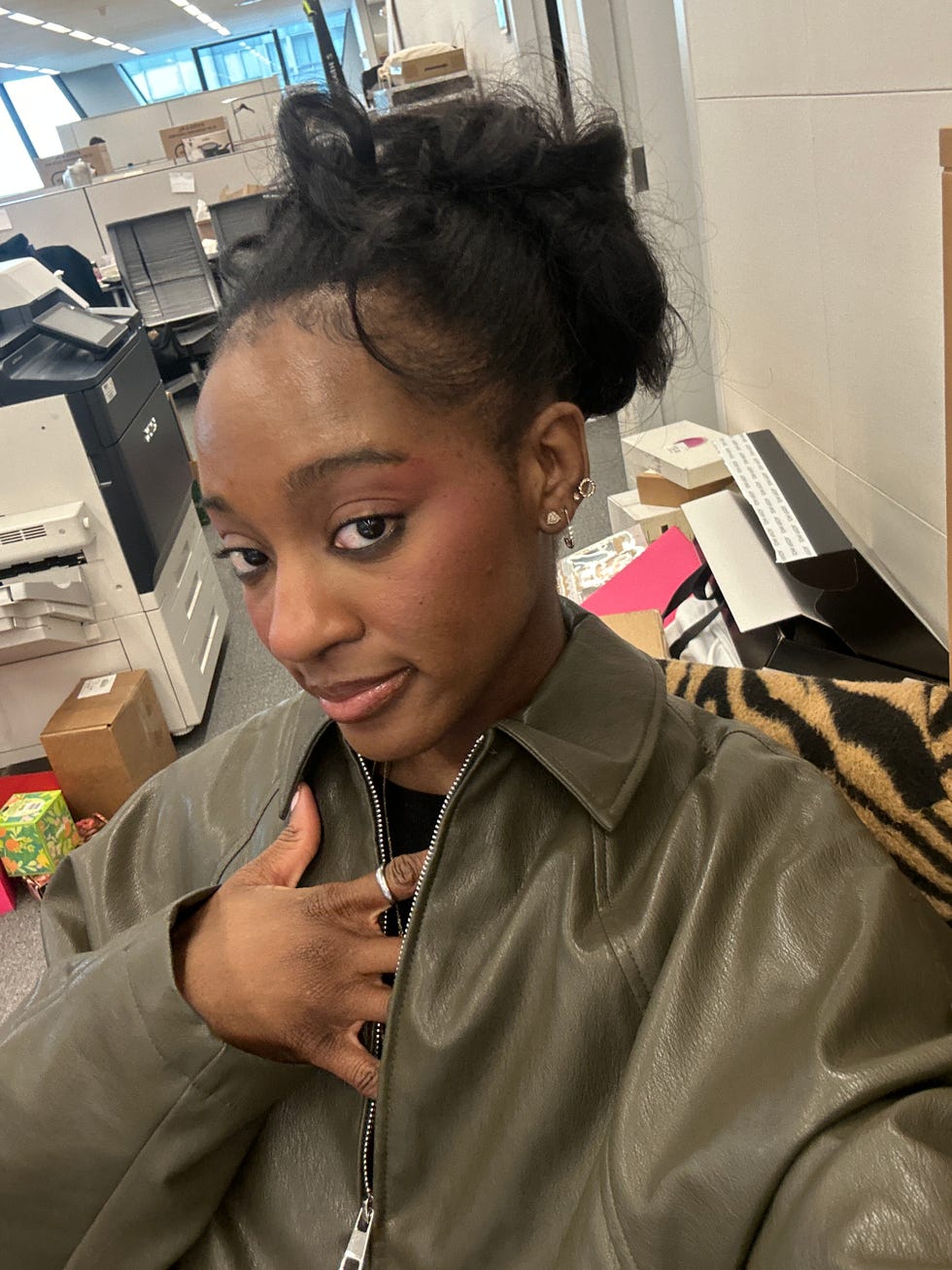 A person in a green jacket making a gesture with their hand.