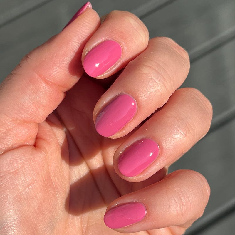Manicure featuring varying shades of pink nail polish on fingers.