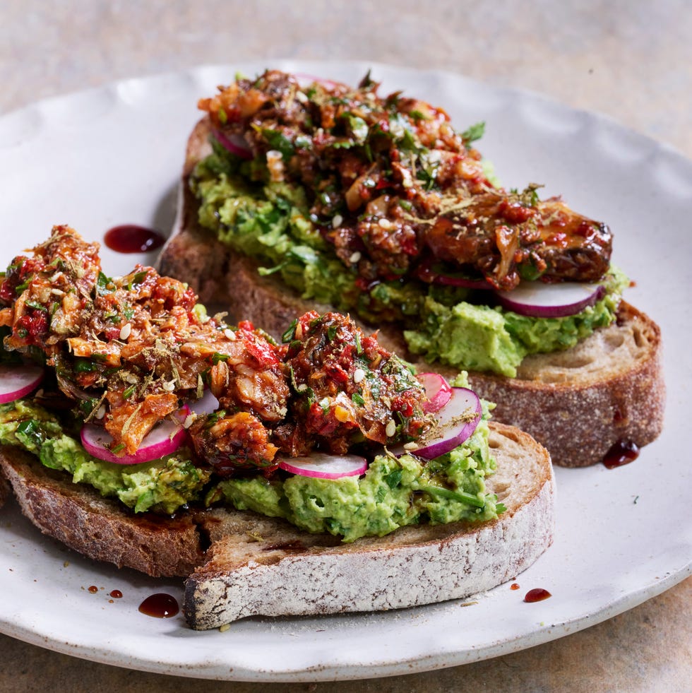 sourdough toast topped with pea and avocado smash, spiced sardines and fresh herbs