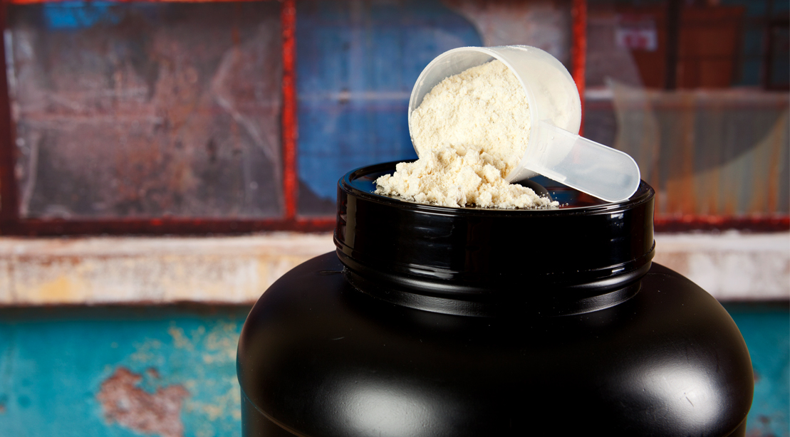 Bottle of creatine protein with the scooper resting on the top