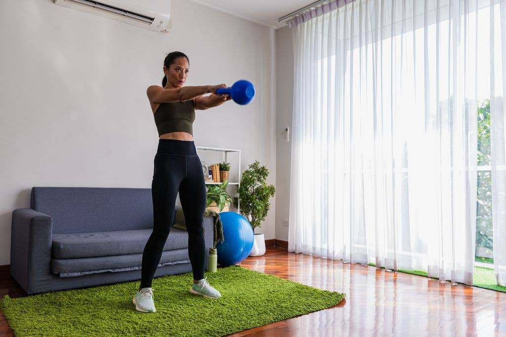 woman in living room doing kettlebell swings workout