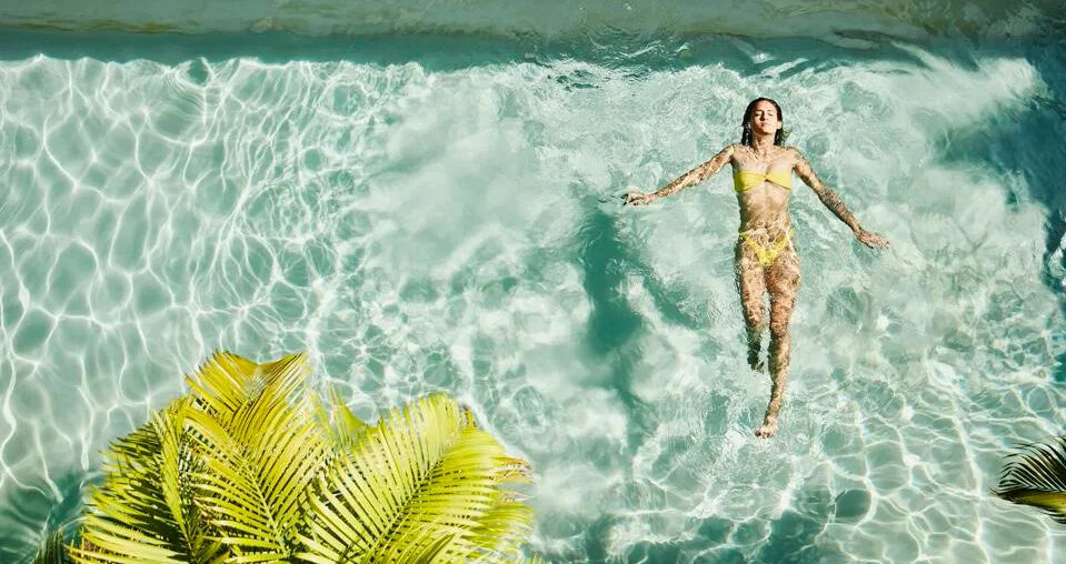 Woman floating in a clear pool at a luxury wellness resort in Mexico.