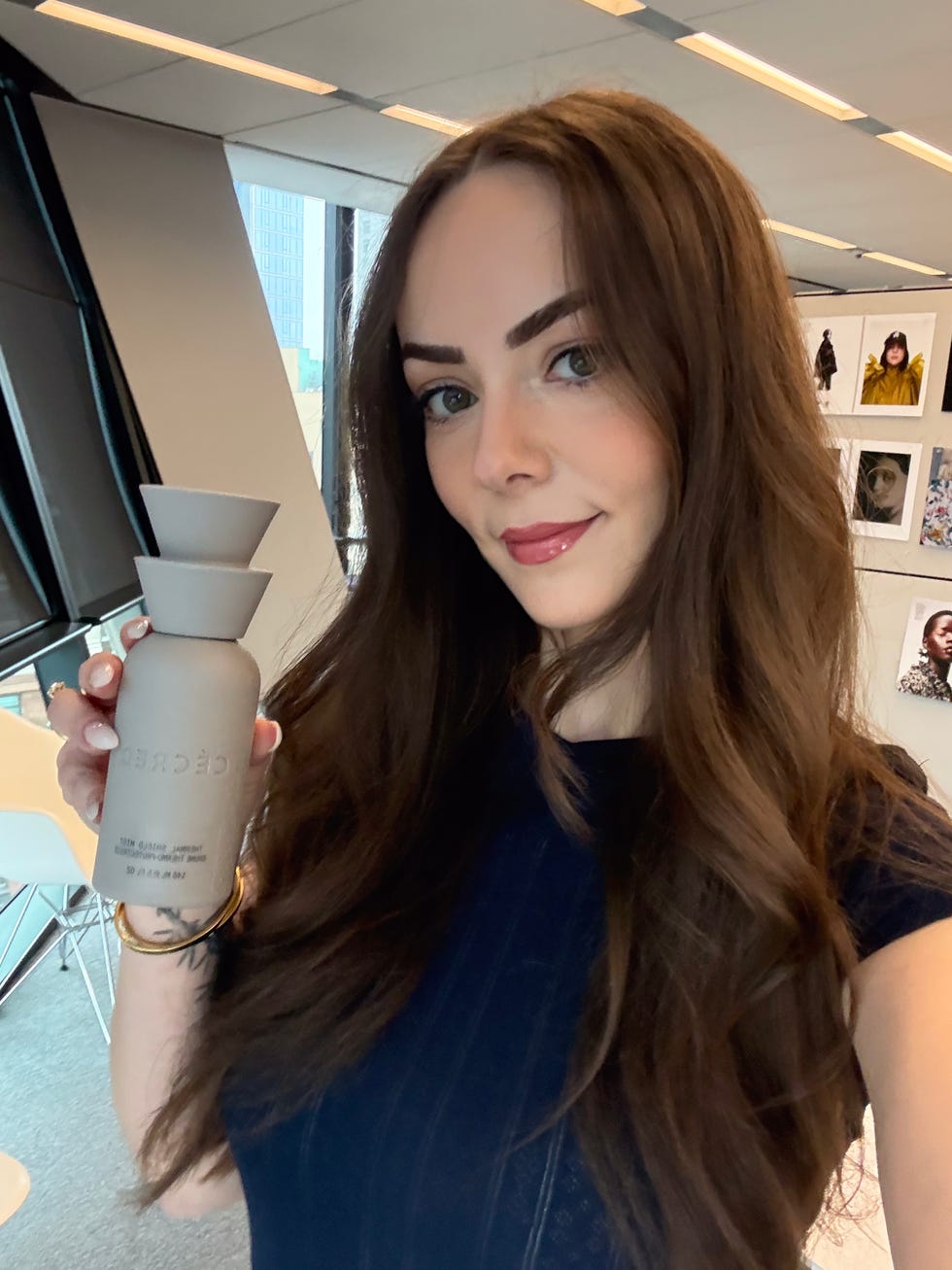 Person holding a skincare product in an indoor modern setting.