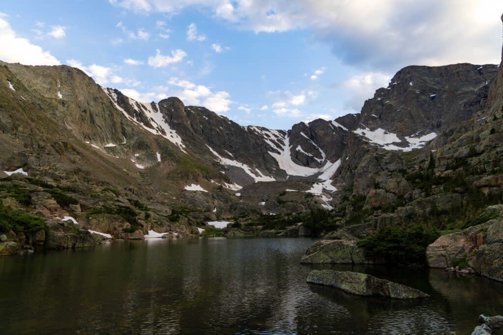 Glass Lake just below sky pond in the rockies. Clouds hover over the tops of the peaks