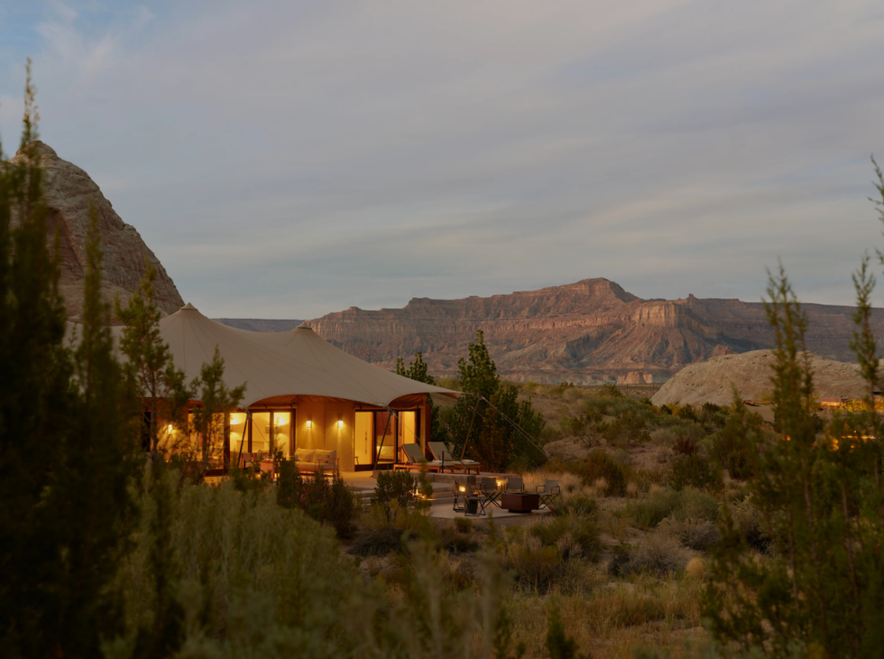 Spacious tent accommodation set in a desert landscape with mountains in the background.