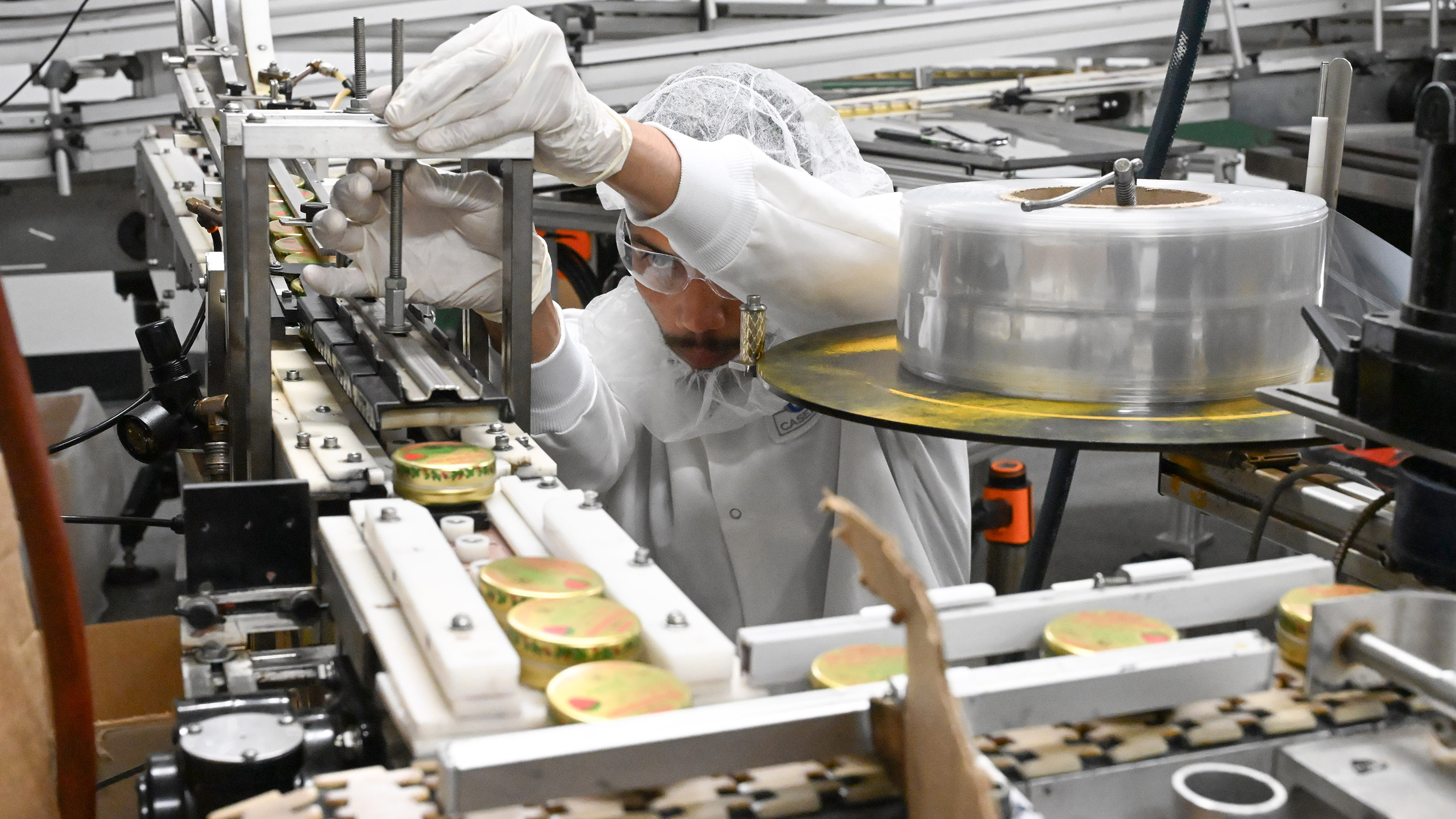 Eli Morales makes adjustments to a device capping the tins...